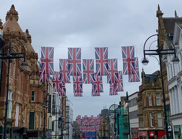 Union Jack flags flying above a pedestrianised street in Leeds city centre
